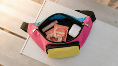 Open belt bag with a Swoon condom, lip balm and earbuds inside