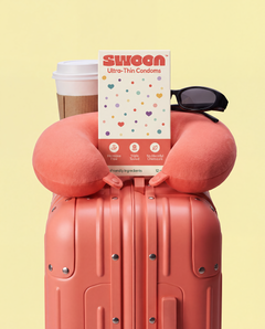 Swoon condom box on a pink suitcase, ready for travel